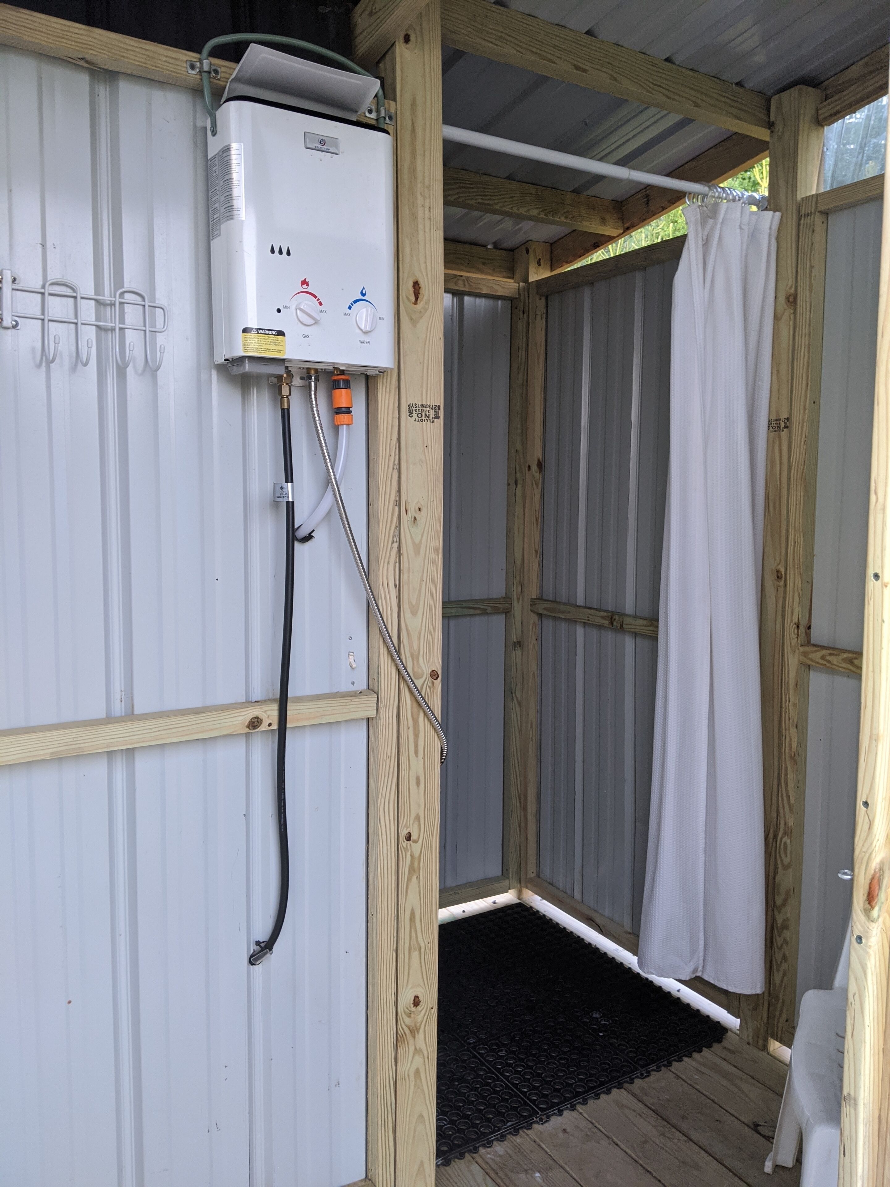 Eine tragbare Sauna mit Bedienfeld, einer Duschkabine und einer Holzterrasse.