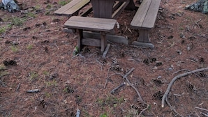 Ein Picknicktisch mit Bänken in einem bewaldeten Gebiet.