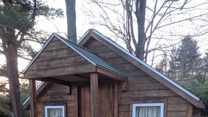 Eine kleine Holzhütte mit Veranda, zwei Fenstern und einer Tür.
