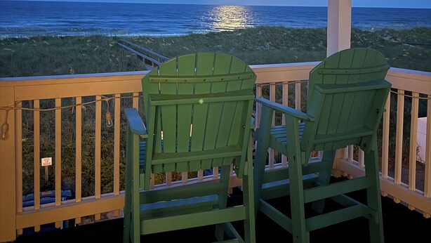 A balcony with two green Adirondack chairs facing a beach at sunset. - “BEACHFRONT ELM” IS CALLING
~Oceanfront~Private Beach Access~Pool~ (Carolina Beach)