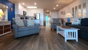 A modern living room with a blue sofa, a white coffee table, and a patterned armchair. - “BEACHFRONT ELM” IS CALLING
~Oceanfront~Private Beach Access~Pool~ (Carolina Beach)