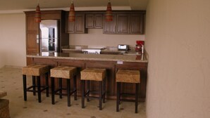 Una cocina con armarios de madera, una isla integrada con taburetes de bar e iluminación colgante.