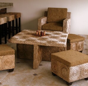 A room with a woven-texture sofa and ottoman set, a matching coffee table, and a bar area with stools.
