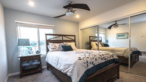 A bedroom with a large bed, a nightstand, a mirror, and a ceiling fan. - Ocean View 2 Bdrm / 2 Bath Beach Condo in San Diego (Pacific Beach) (San Diego)