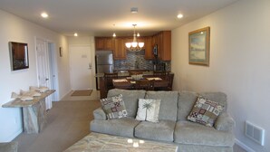 A living room with a grey sofa, a marble coffee table, and a kitchen in the background. - Ocean View 2 Bdrm / 2 Bath Beach Condo in San Diego (Pacific Beach) (San Diego)