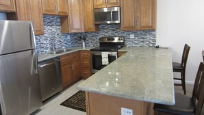 A kitchen with wooden cabinets, a stainless steel refrigerator, a microwave, and a stove. - Ocean View 2 Bdrm / 2 Bath Beach Condo in San Diego (Pacific Beach) (San Diego)