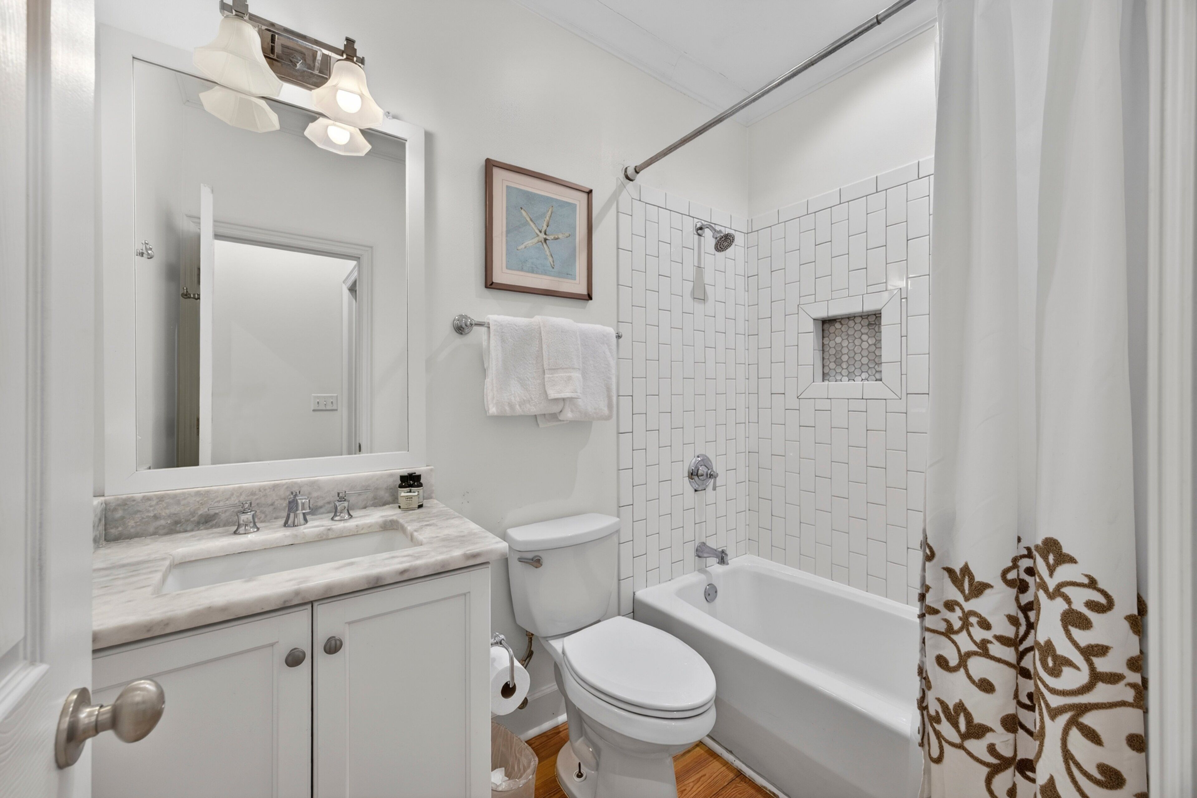 Un baño con inodoro, lavamanos, espejo, ducha y bañera.