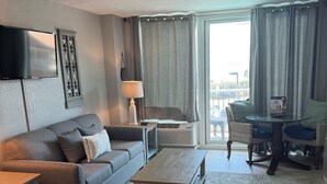 En moderne stue med sofa, sofabord og fjernsyn ophængt på væggen.