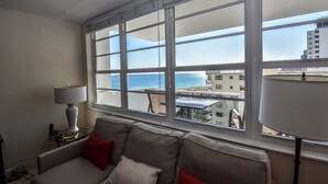 A room with a large window, a sofa, and a lamp. - Between Lowe's and Ritz Carlton Hotels Beachfront on Lincoln (Miami)