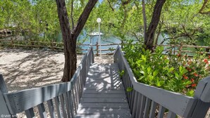 A wooden boardwalk leading to a body of water, surrounded by trees and a fence. - Key Largo Kawama Villa L1, 3/3 (Key Largo)