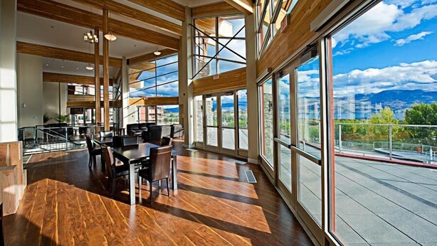 A spacious interior with high ceilings, large windows offering a view of the outdoors, and a modern wooden floor. - Lake View! Resort Style living. Short term rentals are allowed  at this complex. (Westbank, Kelowna)