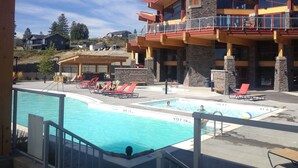 A resort with a pool area, lounge chairs, and a large building with multiple balconies. - Lake View! Resort Style living. Short term rentals are allowed  at this complex. (Westbank, Kelowna)