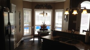 A kitchen with a central island, a refrigerator, and a dining area with a table and chairs.