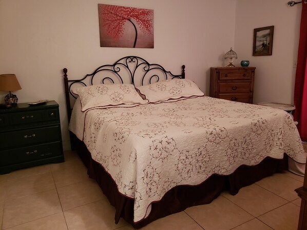 Une chambre à coucher comprenant un lit, une commode, une table de chevet et un mur orné de deux tableaux.