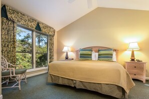 A bedroom with a large bed, two bedside lamps, a wooden nightstand, a chair, and a window with curtains. - FREE GOLF, TENNIS, POOLS & BEACH MANAGED BY WESTIN RESORT & SPA- 3 Bdrm/3 BATH  (Hilton Head Island)