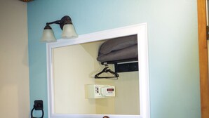 Un baño con tocador de madera, un espejo con lámpara y un perchero para toallas, además de un jabonera.