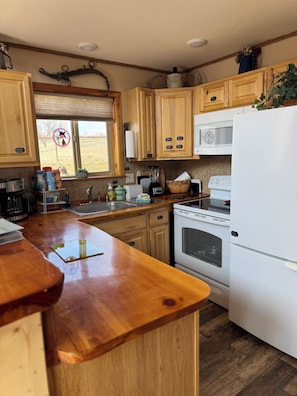 A kitchen with wooden cabinets, a white refrigerator, a microwave, and a stove.