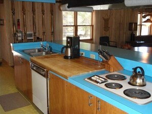 Enjoy cooking in this well-lit kitchen with a stove, coffee maker, and wooden cutting board.