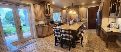 A kitchen with a central island, granite countertops, and a view of a garden through the sliding doors.