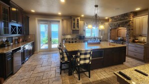 A spacious kitchen with granite countertops, dark cabinetry, and a large island.