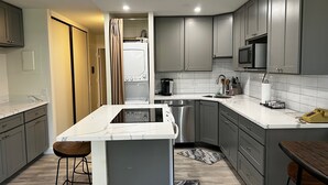 A modern kitchen with grey cabinets, a white marble countertop, stainless steel appliances, and a built-in microwave. - UPDATED MAUI VACATION RENTAL (Kihei)