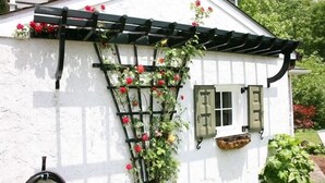 A white building with a black pergola and red flowers. - Cottage on Historic Gentleman's Farm (Chester Springs)
