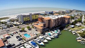 Un puerto deportivo con barcos amarrados, una piscina y un hotel con varias edificaciones y balcones.