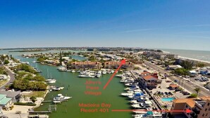 An aerial view of Madeira Bay Resort 401 with marina, buildings, and a beach. - Beautifully Updated Madeira Bay Resort Unit 401 - Steps from Sand and Fun! (Madeira Beach)