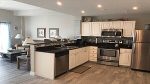A modern kitchen with white cabinets, stainless steel appliances, and a black countertop. - Beautifully Updated Madeira Bay Resort Unit 401 - Steps from Sand and Fun! (Madeira Beach)