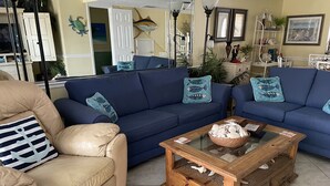 A living room with two sofas, a coffee table, and a beige armchair.