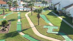 A golf course with multiple green lanes and a central water hazard.