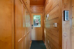 A wooden hallway with a door, a thermostat, and a small window.