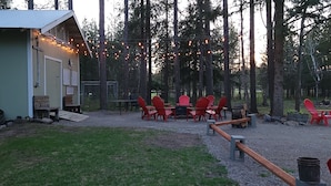 Een rustieke hut met een eethoek met rode stoelen en een tafel, omringd door een bos.