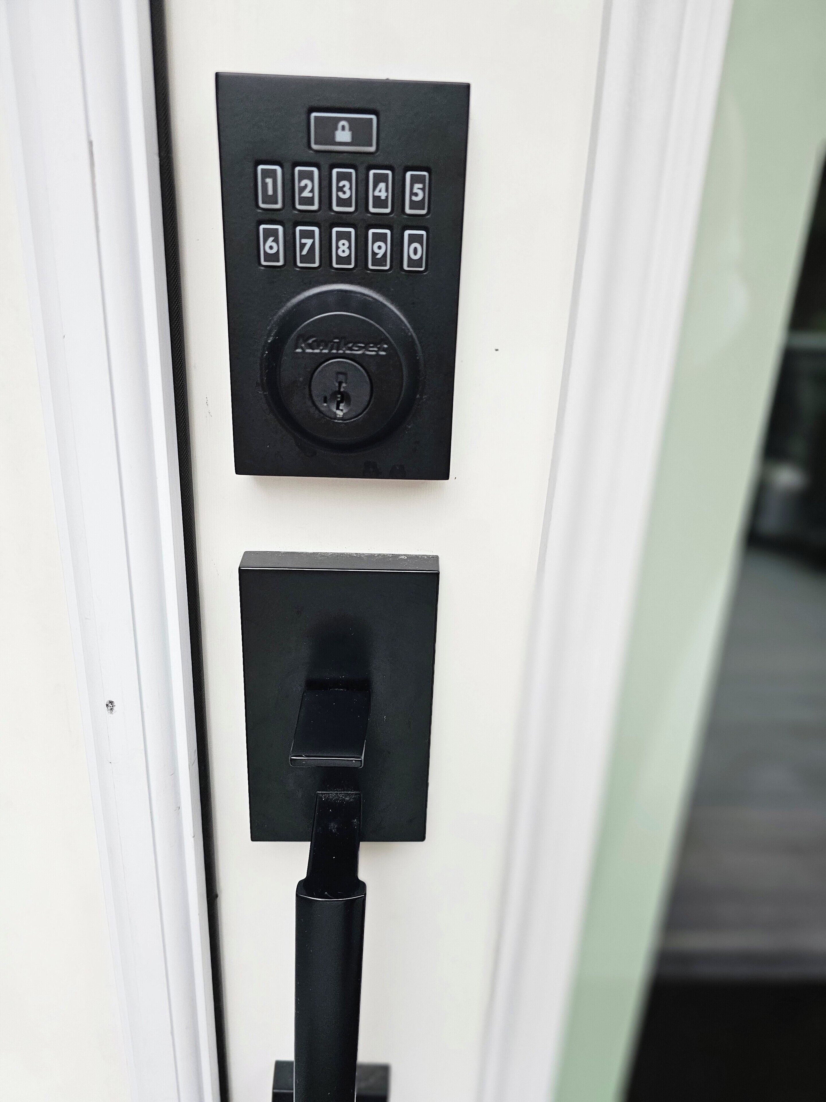 A keypad lock mechanism on a door, a keyhole below it, and a key inserted into the keyhole.