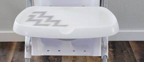 Un déambulateur blanc doté d’un siège et d’un dossier rembourrés, et dont l’assise présente un motif en zigzag.