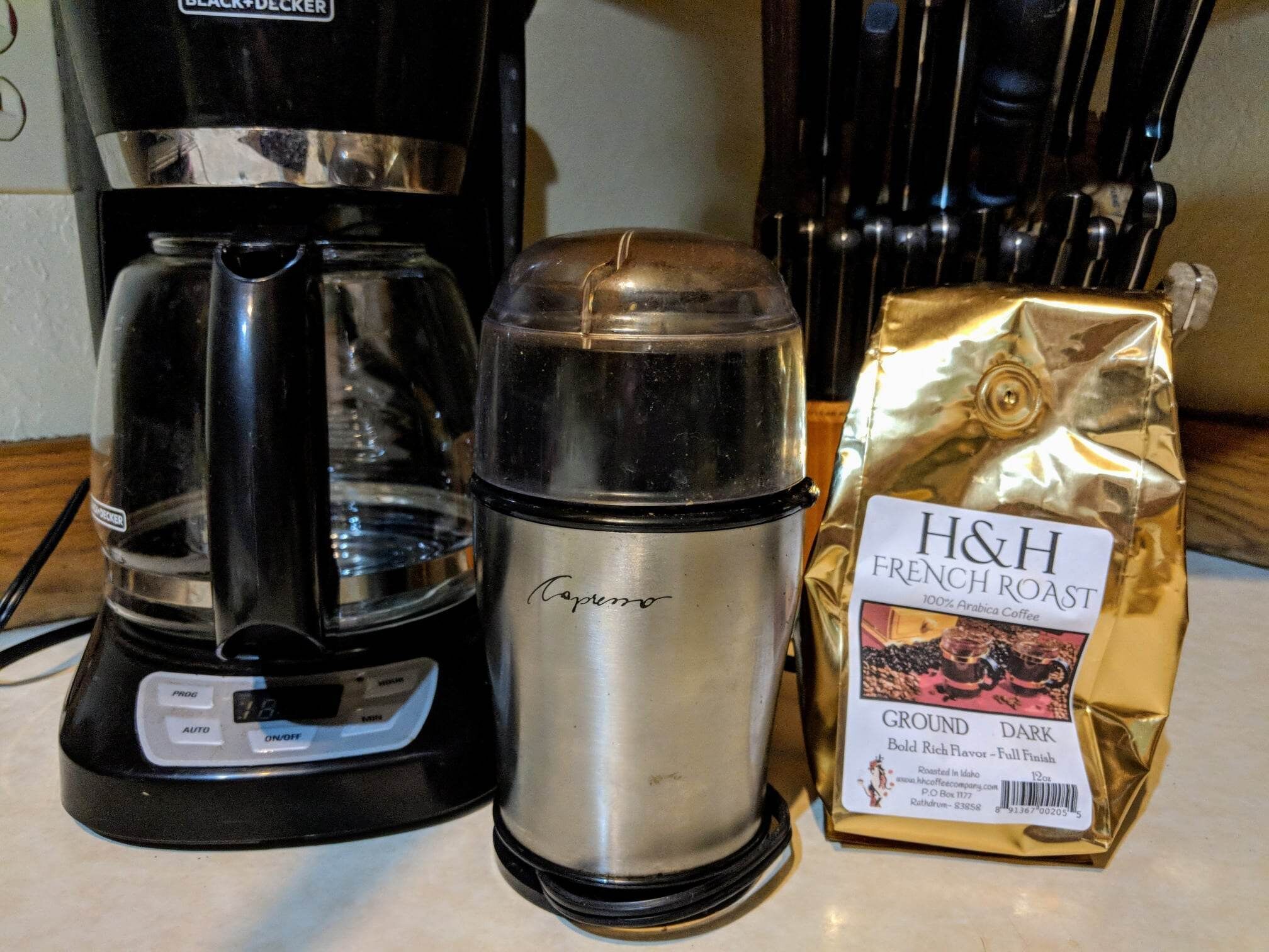 Una cafetera, un termo y una bolsa de café tostado francés H&H sobre una encimera de cocina.