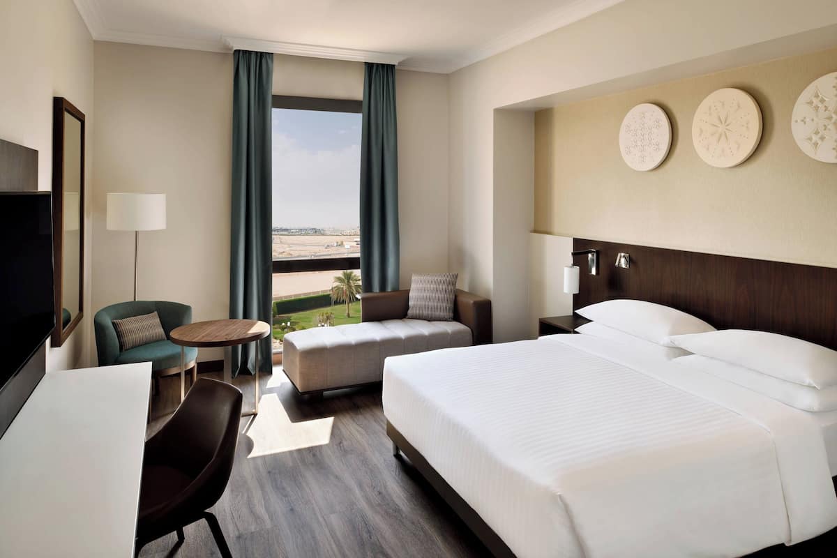 Ein Hotelzimmer mit einem großen Bett, einer Couch, einem kleinen Tisch und einem Fernseher.