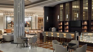 Un moderno vestíbulo de hotel con zona de bar, arreglos de asientos y una vitrina.