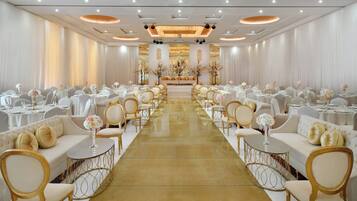 A banquet hall with rows of round tables, white chairs, and a central aisle.