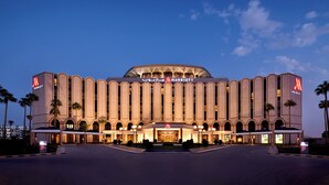 Un hotel grande y moderno con un llamativo letrero de Marriott, varias entradas y una fachada simétrica.