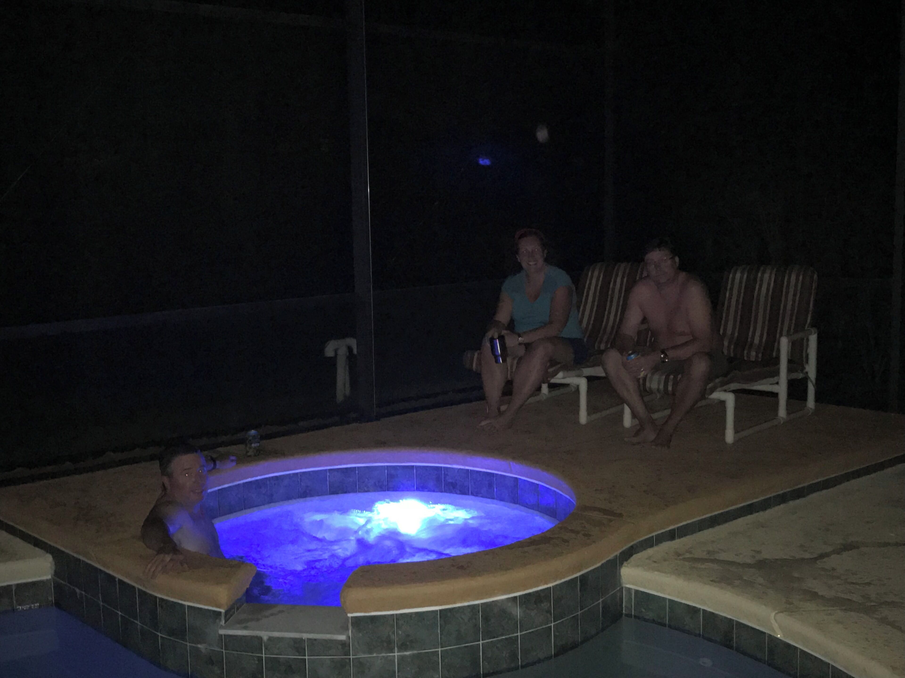 A hot tub area with a tiled floor and a person sitting in the tub.