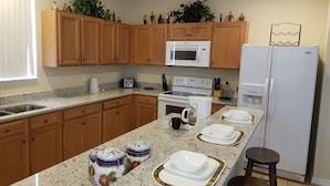 A kitchen with wooden cabinets, a microwave, a stove, a sink, and a refrigerator. - SOUTH FACING POOL/SPA - ALL DAY SUN - FREE BBQ/WIFI/CALLS - GAMES ROOM - 5 BR (Davenport)