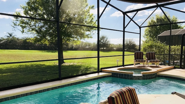 A pool area with a glass enclosure, a hot tub, and striped chairs. - SOUTH FACING POOL/SPA - ALL DAY SUN - FREE BBQ/WIFI/CALLS - GAMES ROOM - 5 BR (Davenport)