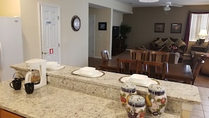 A kitchen with granite countertops, a coffee maker, and jars. There is a dining area with a table and chairs. - SOUTH FACING POOL/SPA - ALL DAY SUN - FREE BBQ/WIFI/CALLS - GAMES ROOM - 5 BR (Davenport)