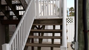 A wooden staircase with white railings leading to a deck area.
