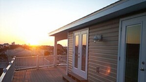 A wooden deck with a railing, a door, and a window.