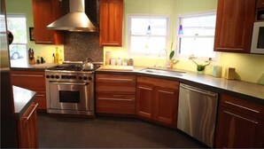 Una cocina moderna con armarios de madera, electrodomésticos de acero inoxidable y un amplio ventanal que proporciona luz natural.