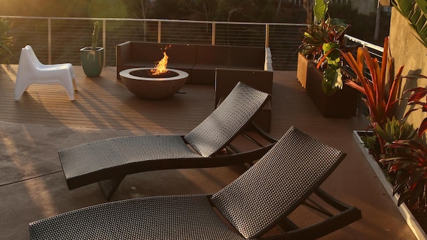 Terraza al aire libre con dos sillones de descanso, un brasero y macetas con plantas.