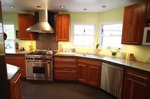 Una cocina moderna con armarios de madera, electrodomésticos de acero inoxidable y un amplio ventanal que proporciona luz natural.