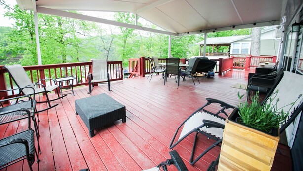 Une terrasse couverte, aménagée avec du mobilier d’extérieur, un barbecue et un jardinier avec des plantes.
